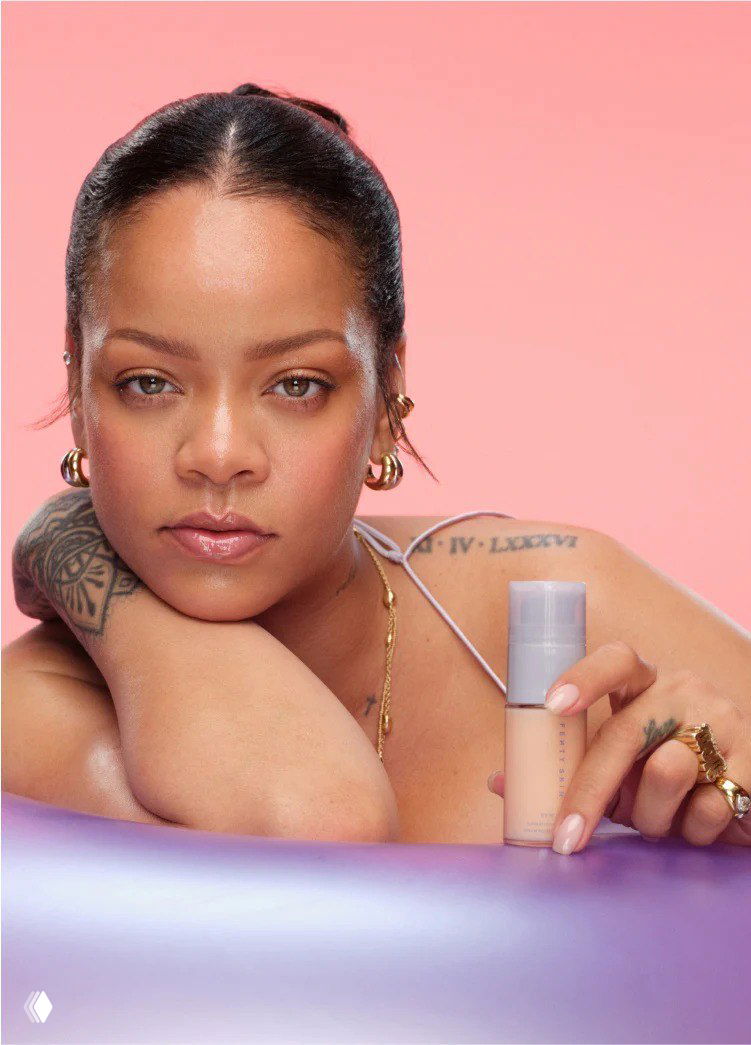 Портретная фотография женщины с косметическим флаконом тонального крема на пастельно-розовом фоне — рекламный образ продукта.