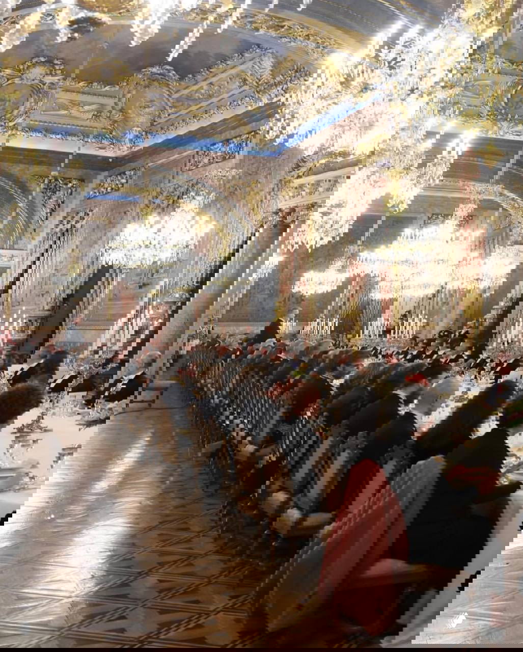 Банкетный зал дворца с длинным столом, сервировкой и деталями интерьера — приём в честь президента Германии с множеством гостей за столом.