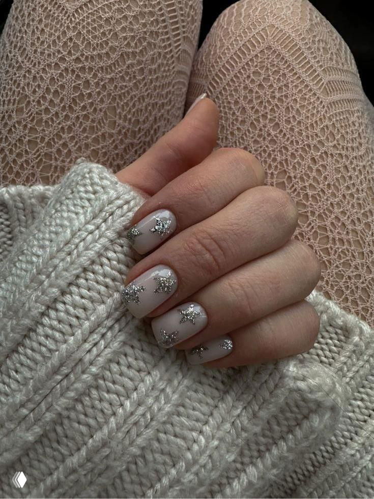 Рука в вязаном свитере с матовым светлым маникюром и серебристым блестящим декором в виде звёздочек на ногтях, тёплый образ.