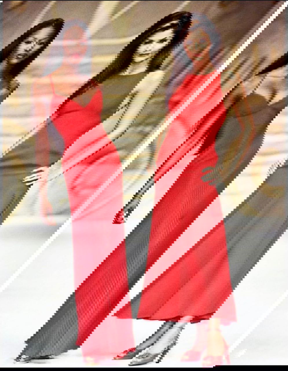 Две модели в элегантных красных платьях позируют рядом друг с другом на подиуме; строгие линии и вечерний стиль коллекции.