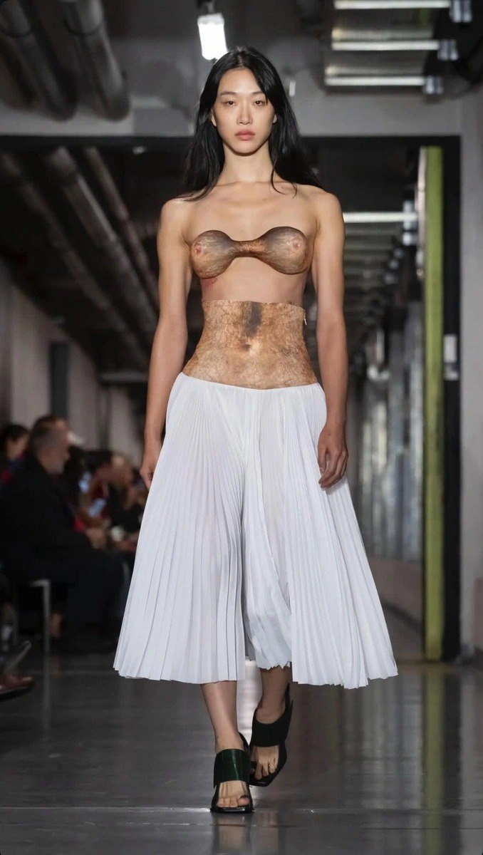 Модель в минималистичном топе и плиссированной белой юбке — один из образов коллекции Дюрана Лантинка для Jean Paul Gaultier на показе.