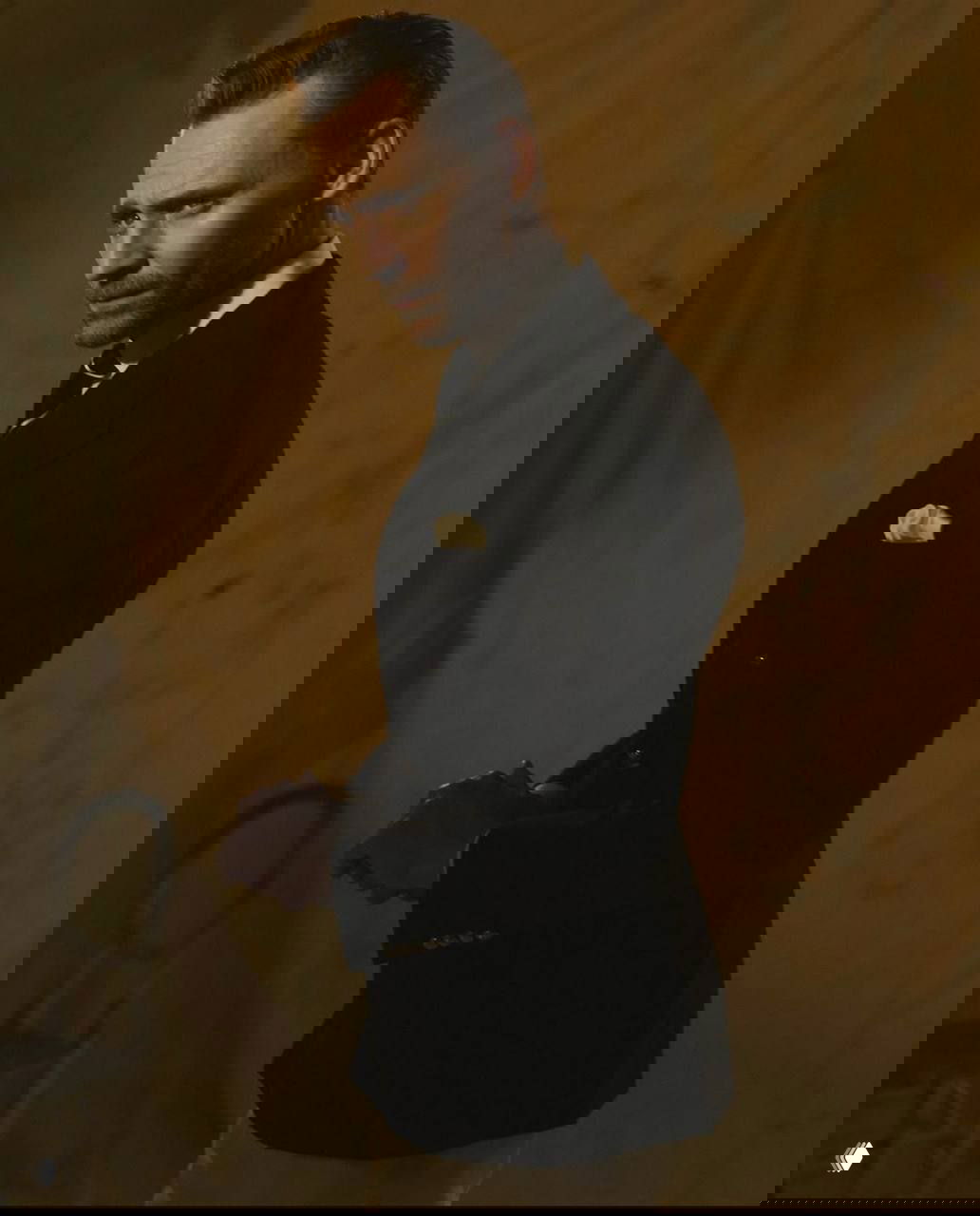 Цветной портрет мужчины в тёмном пиджаке и белой рубашке на тёплом фоне, классический элегантный силуэт и приглушённая палитра студийного кадра.