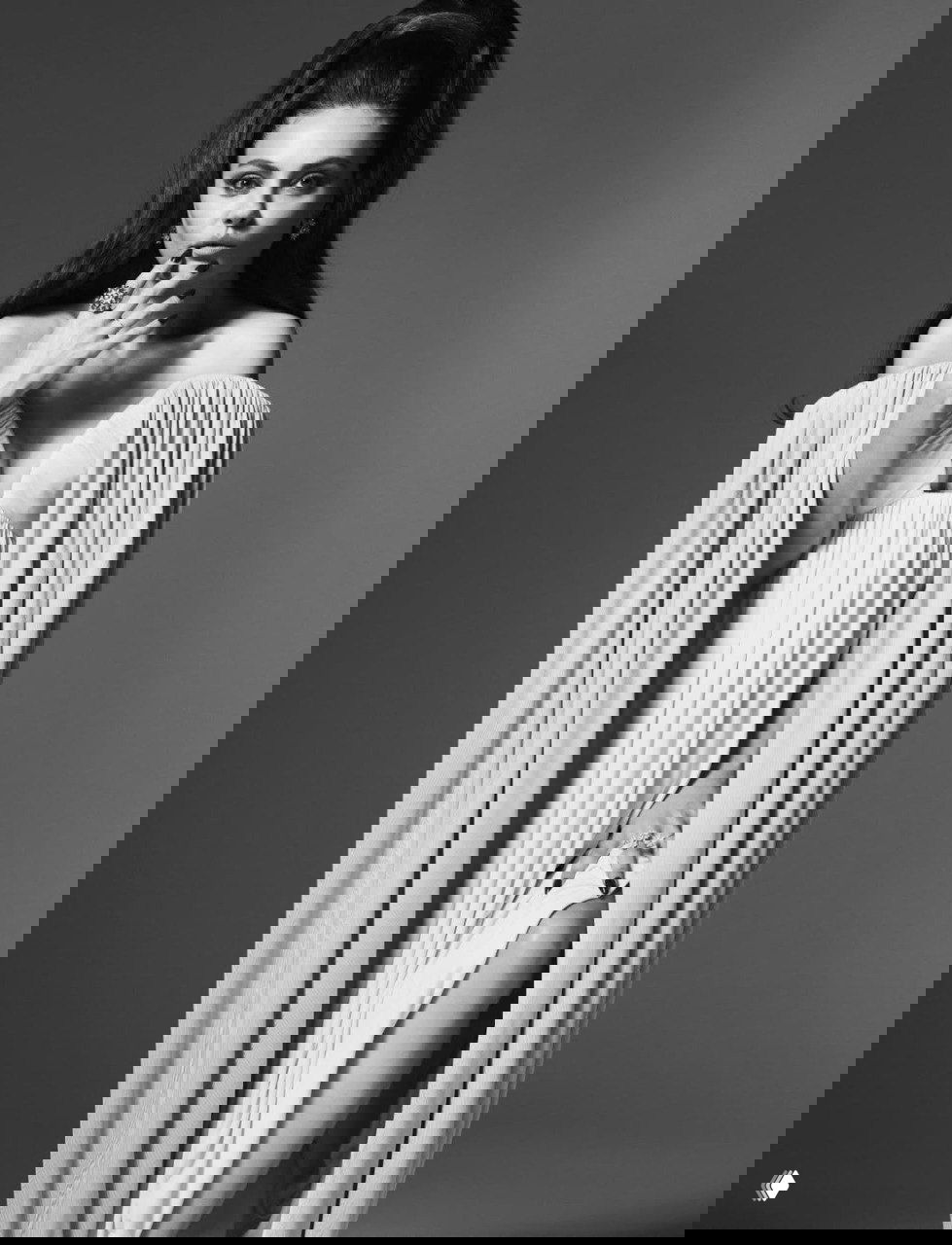 Полноформатный студийный кадр: женщина в длинном платье с глубоким декольте и драпировкой, статичная элегантная поза.