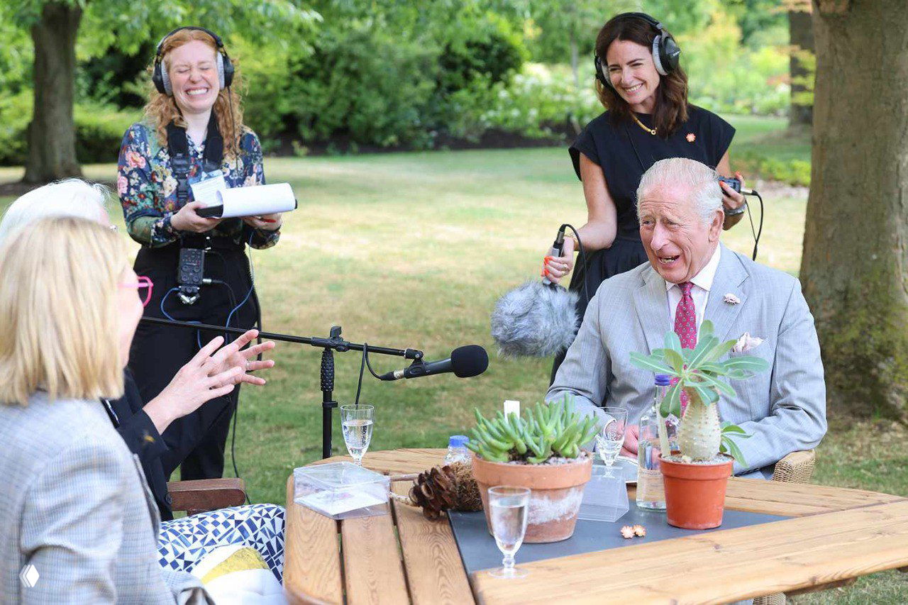 Сцена записи подкаста в саду: король Карл III, техническая команда с микрофонами и участники беседы о семенах и климатических изменениях.