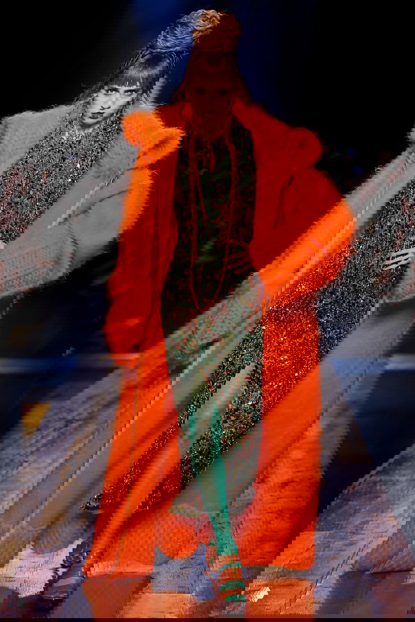 Модель в ярком оранжевом пальто и блестящем платье с зелёными колготками — драматичный образ показа Jean Paul Gaultier 2016.