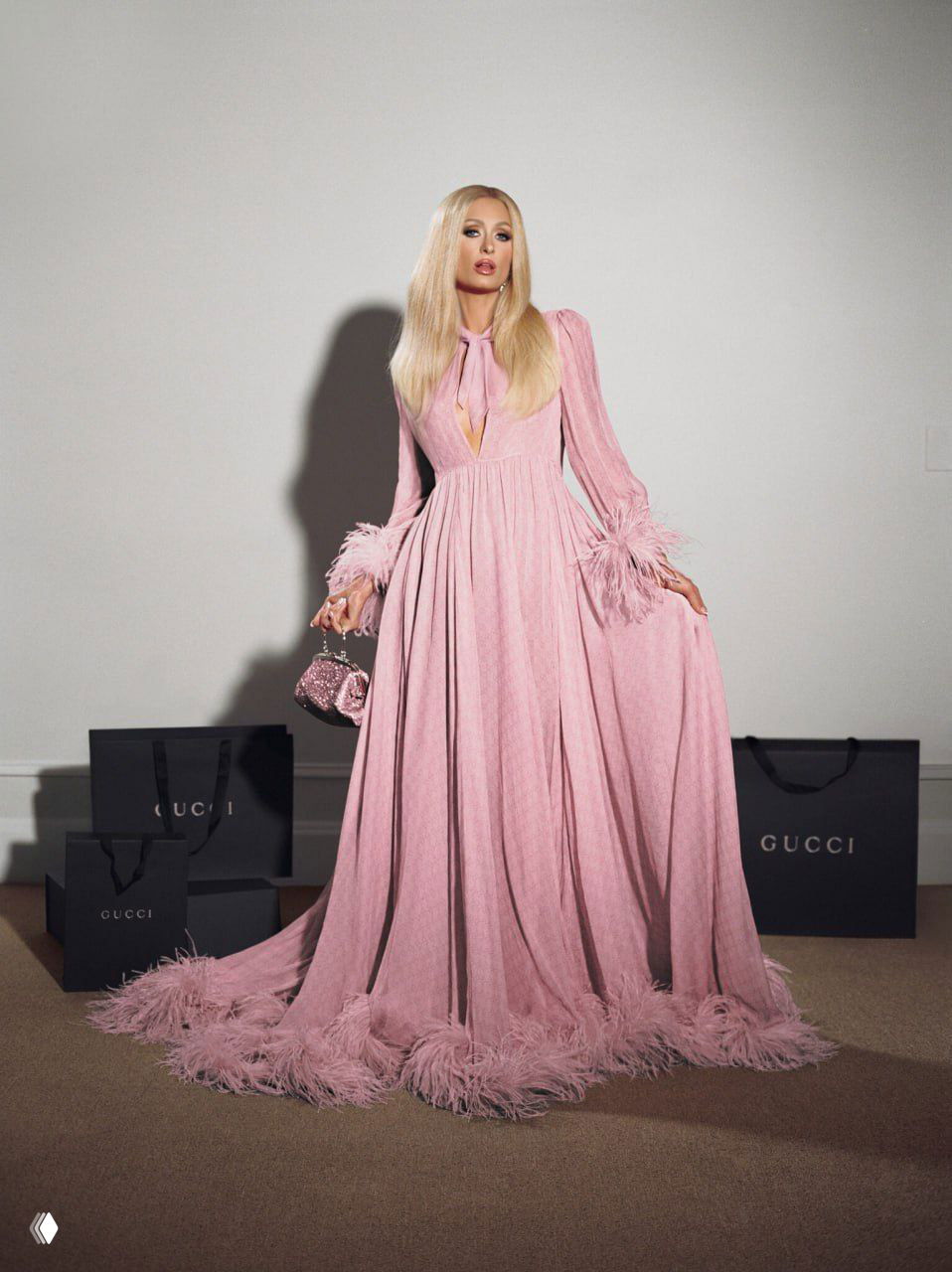 Ростовой портрет в длинном розовом платье с перьевыми манжетами на фоне пакетов Gucci — эффектная студийная фотография в пастельных тонах.