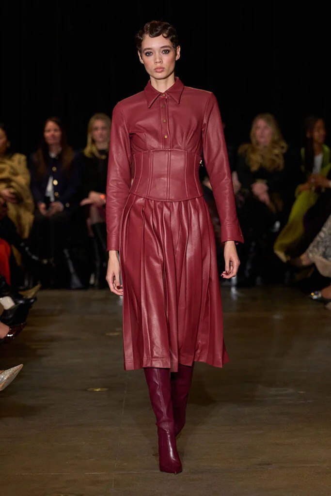 Образ с показа: модель демонстрирует винно-красное кожаное платье и сапоги — лук из коллекции Sergio Hudson осень‑зима 2025 на подиуме.