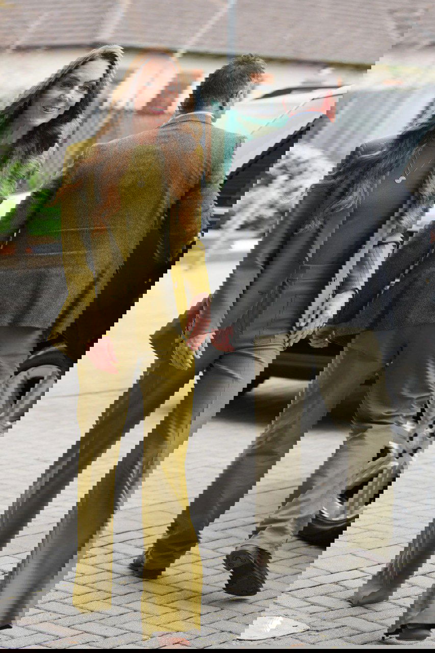 Повседневный оливковый костюм: приталенный пиджак и прямые брюки на городской улице, сочетание делового кроя и мягкой, тёплой палитры.