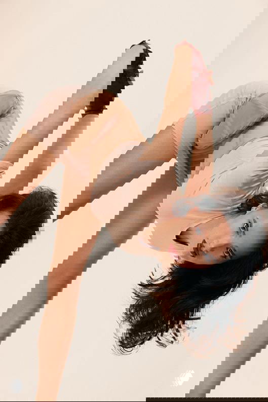 Художественный ракурс фотосессии: Алина Загитова в прогнутой позе на светлом фоне, подчёркнуты линии корпуса и пластика фигуристки.