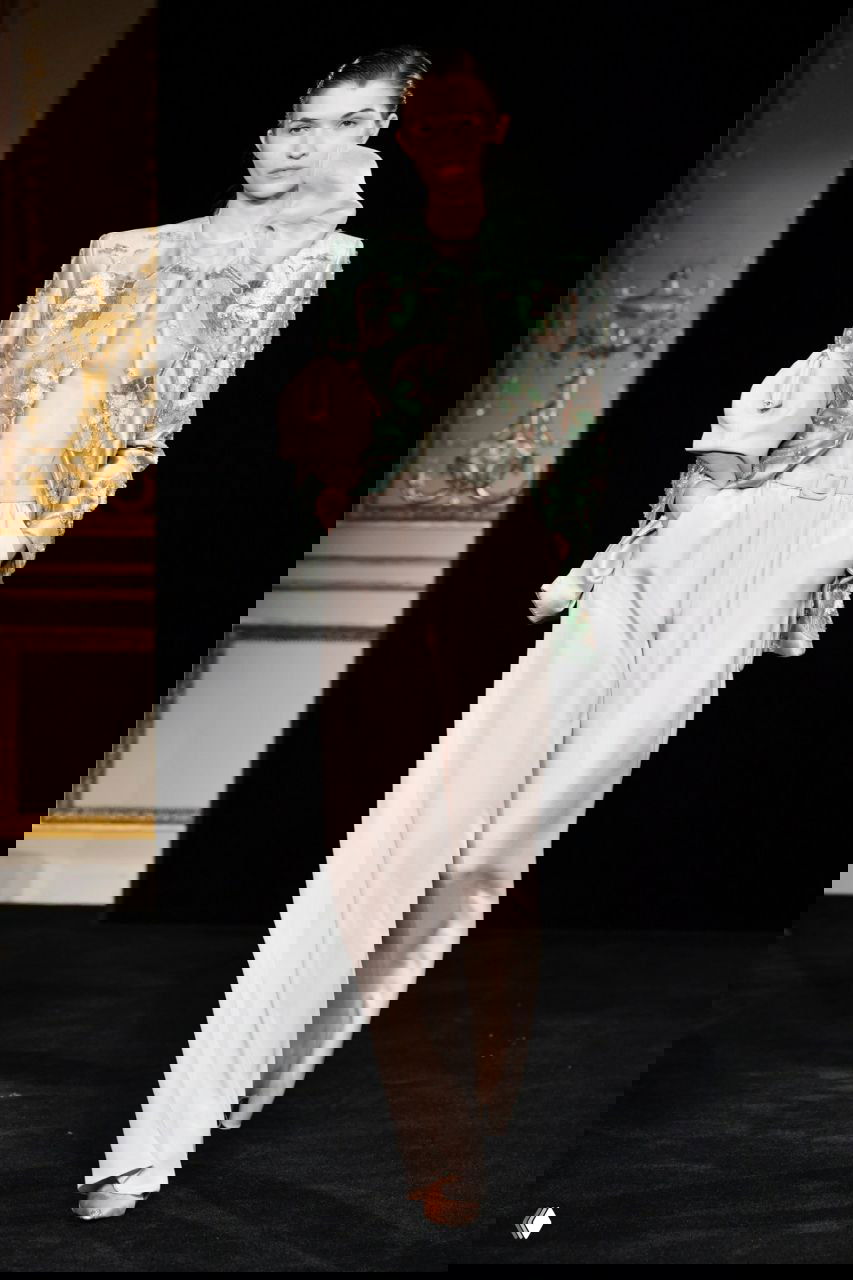 Модель в мятном жакете с цветочной вышивкой и светлыми свободными брюками на кутюрном показе Giorgio Armani, детали аксессуаров и текстур ткани хорошо видны.