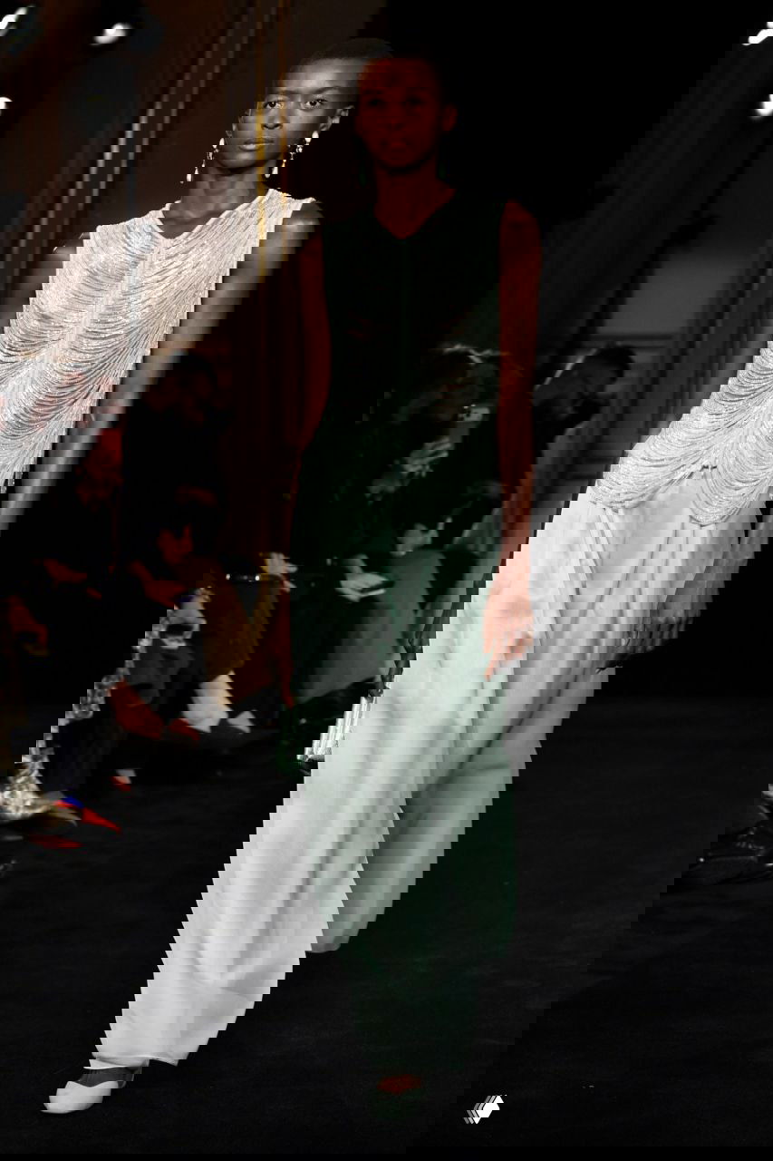 Модель в мятной шелковой блузе с драпировкой и широких сатиновых брюках, образ ретро-элегантности и легкой струящейся посадки ткани на кутюрном показе Armani.