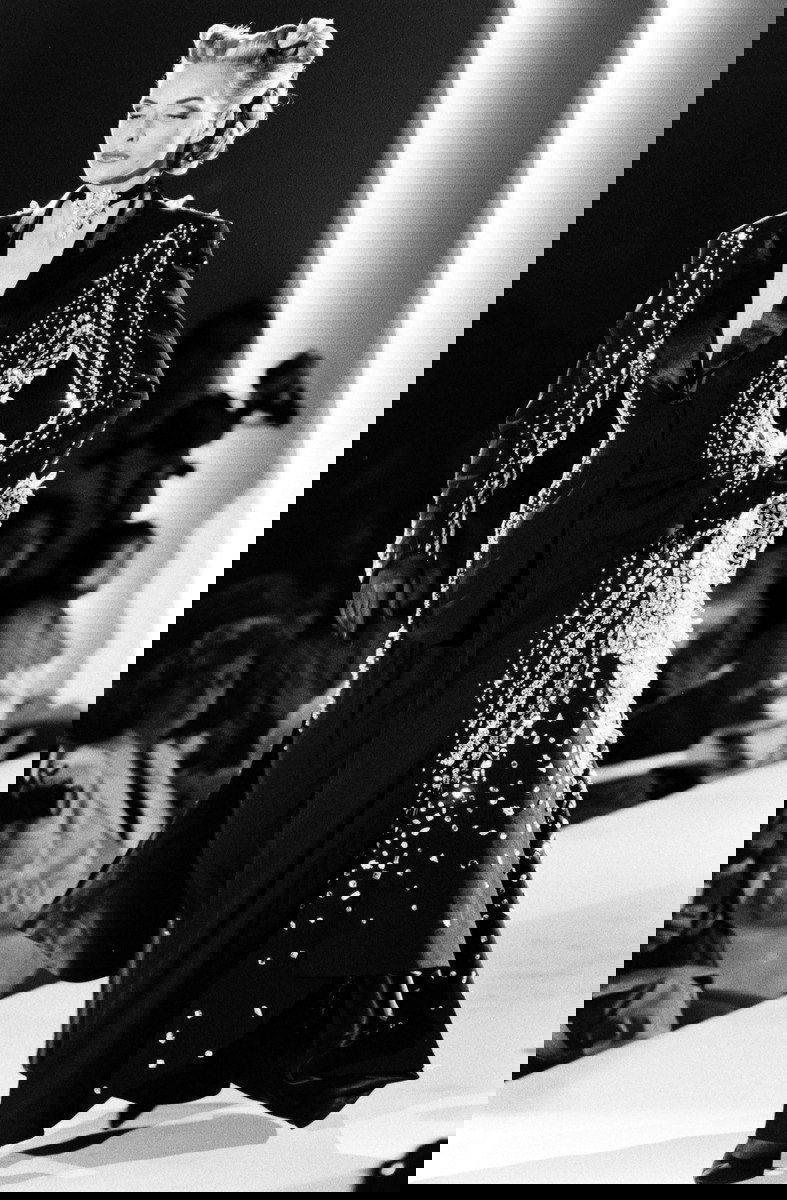 Чёрно-белый кадр с моделью в строгом смокинге с декоративными элементами — сценический образ из архивов высокой моды.