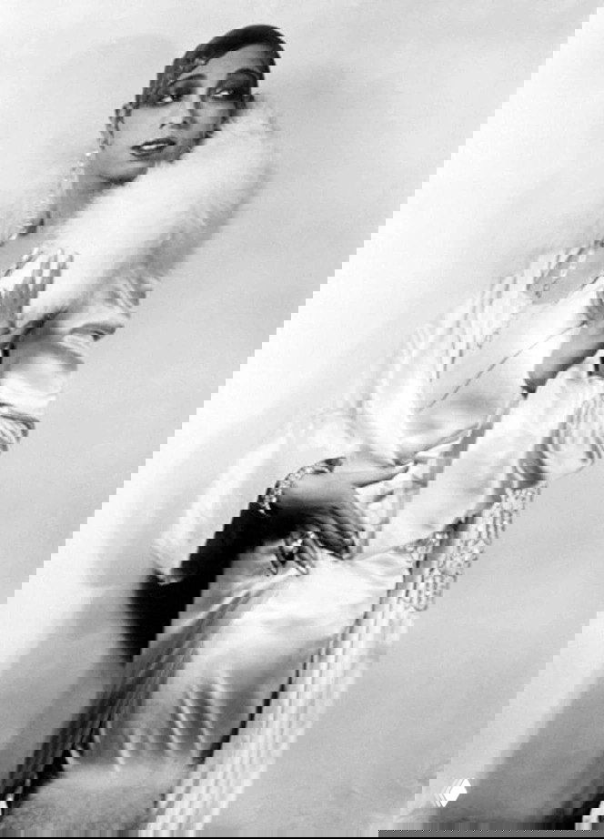 Чёрно‑белая студийная фотография начала XX века: женщина в атласном платье и накидке с пушистой меховой опушкой на плечах, ретро‑гламур.