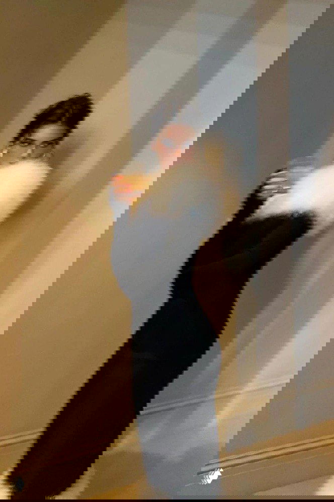 Кендалл Дженнер в чёрном облегающем платье с белой пушистой опушкой на плече и по низу, снимок в движении, интерьерное фото.