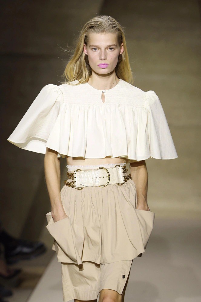 Портрет на подиуме: модель в светлом комплекте с пастельно‑розовой помадой в стиле bubblegum pink, мягкий макияж подчёркивает молодёжный ретро‑камбек оттенка