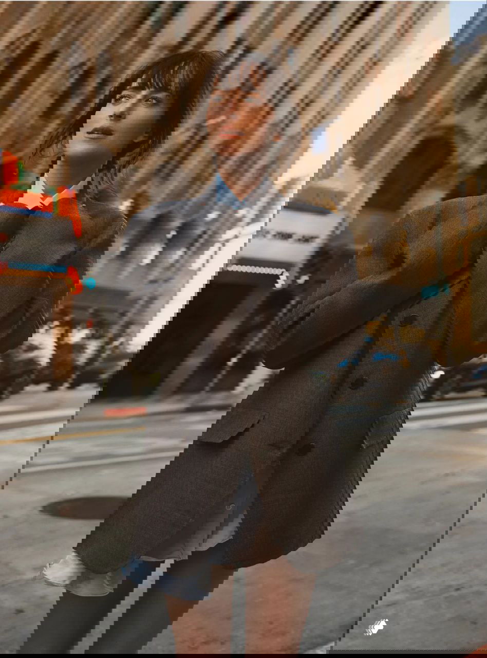 Актриса на уличной съёмке в оверсайз-пиджаке и коротком платье; городской фон, мягкий свет и внимание к слоям и текстурам образа.