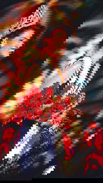 Яркий сценический портрет победительницы с букетом цветов и короной — фото, подчёркивающее стандарты красоты и модные образы нашей эпохи.