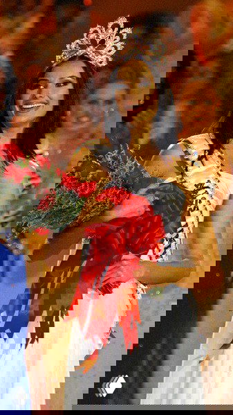 Улыбка победительницы в вечернем платье и короне — современный титульный кадр, демонстрирующий эволюцию макияжа, причёсок и сценического имиджа.