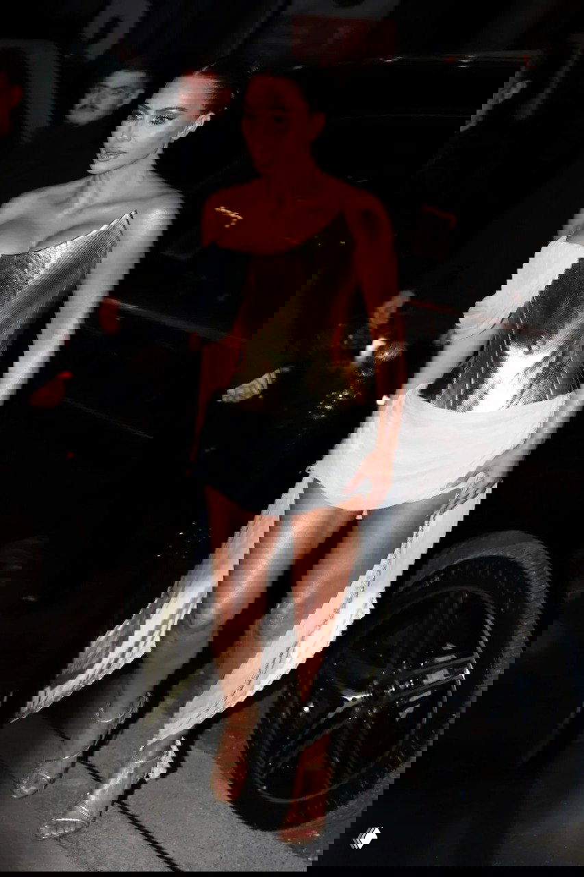 Ким Кардашьян в золотом корсетном платье Givenchy 1997 и белой драпировке идёт по улице вечером, кадр в полный рост