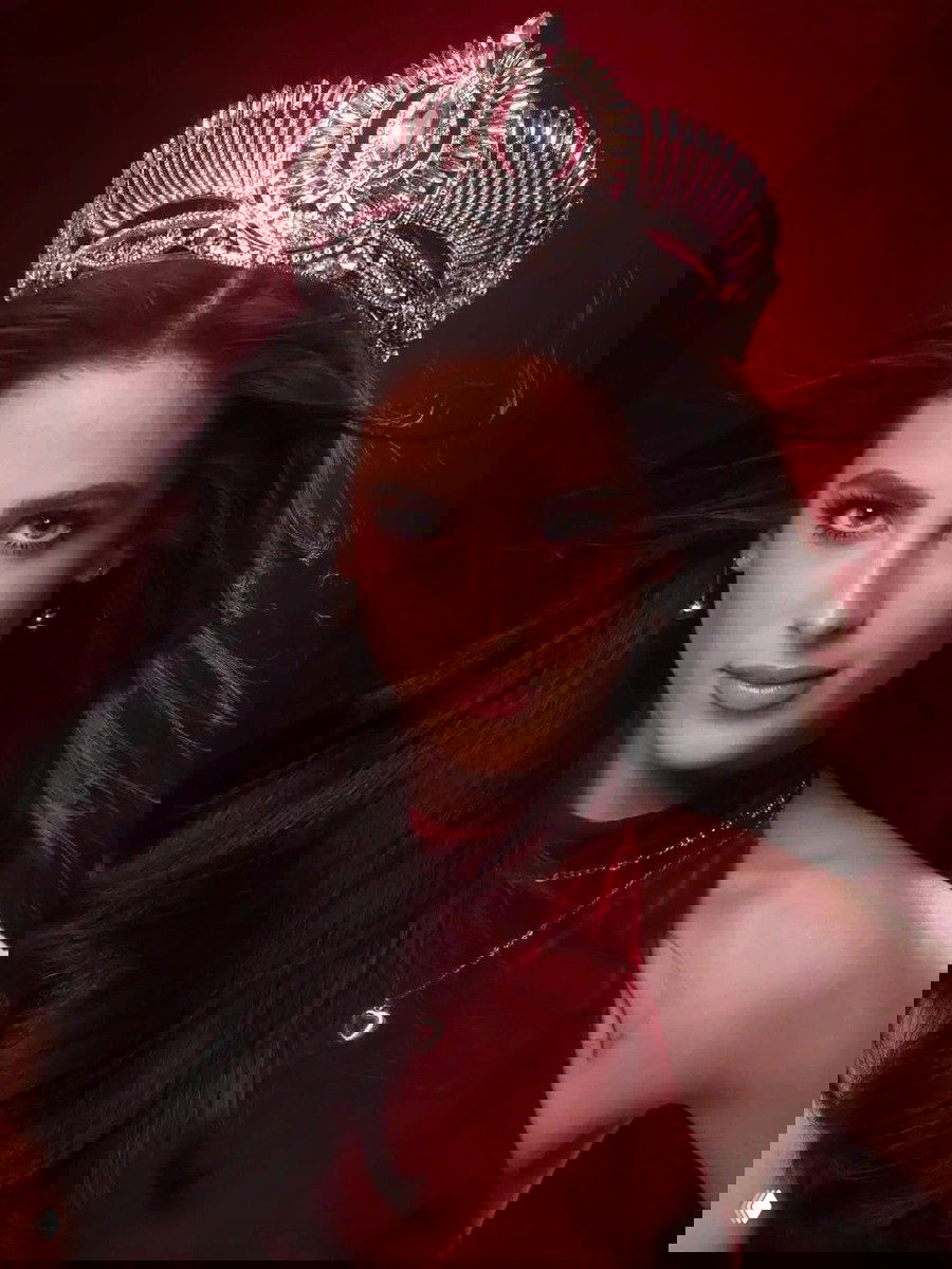 Современный студийный портрет новой победительницы в диадеме на красном фоне — крупный план лица, выразительный макияж и роскошная корона.