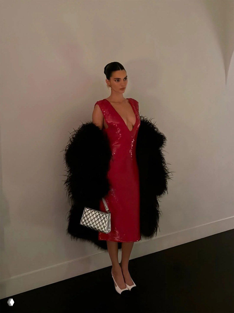 Студийный кадр: женщина в лаковой алой миди-платье с глубоким декольте и чёрной пушистой шубой, в руках серебристая стёганая сумка и двухцветные лодочки.