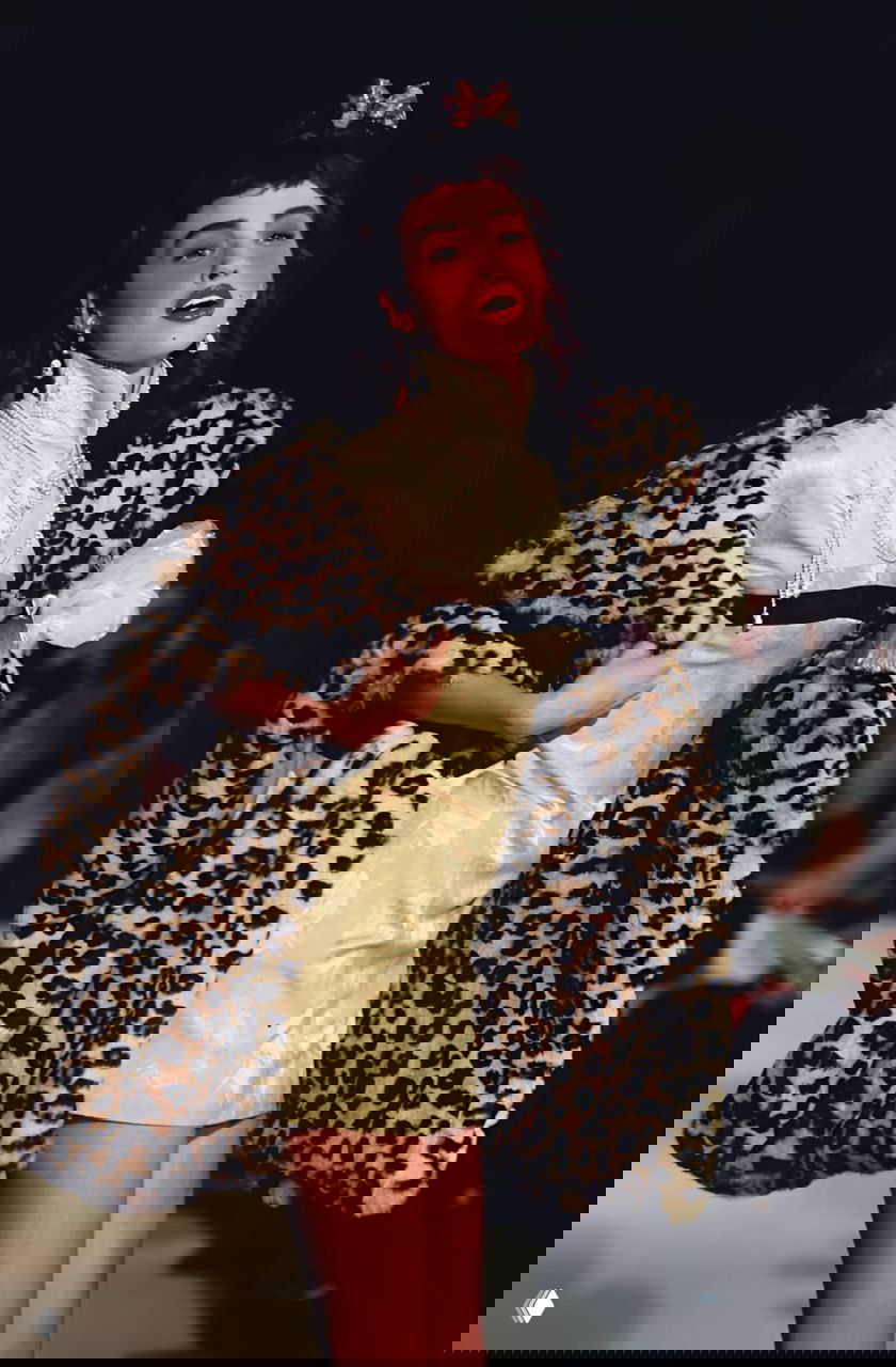 Модель в леопардовой шубе и коротком кремовом платье на подиуме показа Dior осень‑зима 1997, винтажный макияж, жемчужные украшения и зрители.