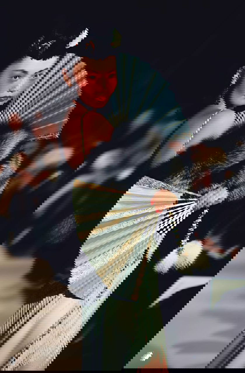 Модель с веером и контрастной меховой накидкой в азиатской стилизации на показе Dior осень‑зима 1997, театральный образ и стилистические детали.