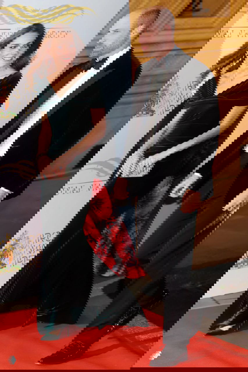 Женщина в тёмно‑зелёном бархатном платье и мужчина в смокинге на красной дорожке у Королевского Альберт‑холла.