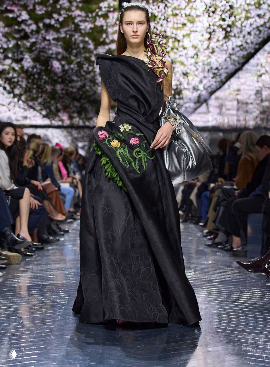 Чёрное асимметричное кутюрное платье с цветочной вышивкой на модели; показ Джонатана Андерсона для Dior и растительные мотивы декора.