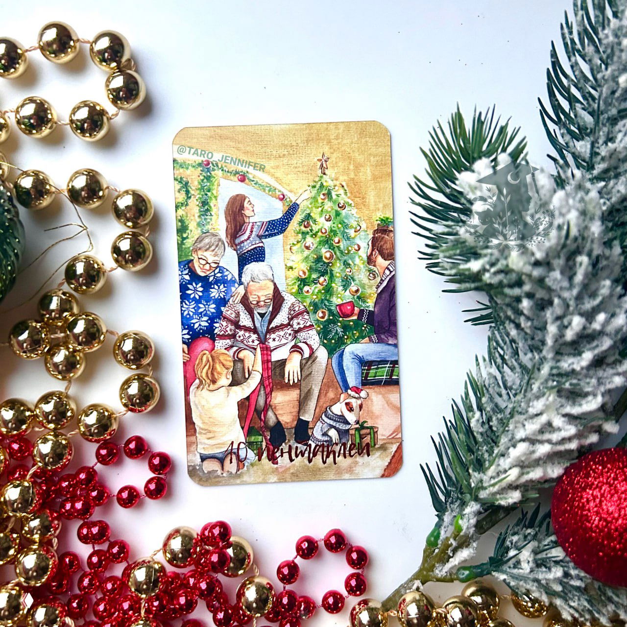 Карта '10 Пентаклей' из колоды «Таро Волшебной Зимы» на белом фоне среди праздничных бус и заснеженной ветки ёлки.