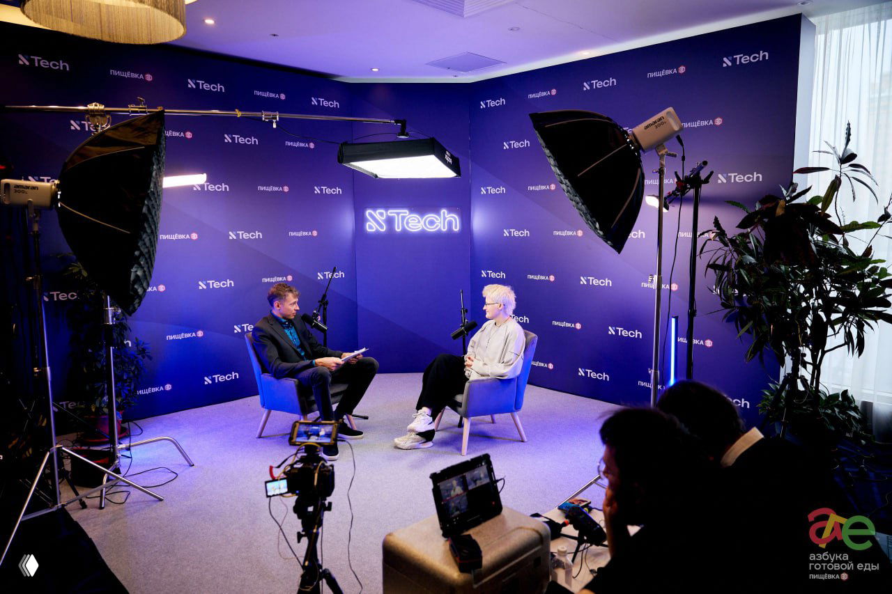 Интервью-зона XTech: оборудованная студия с осветительными приборами, камерой и двумя участниками беседы в креслах на фоне брендированной стены.