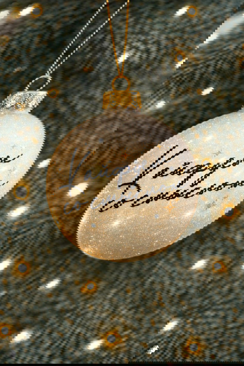 Глиттерный ёлочный шар с надписью «Кайфуем со смыслом» — основной слоган Пищёвки, подвешенный на еловой ветке и освещённый гирляндой.