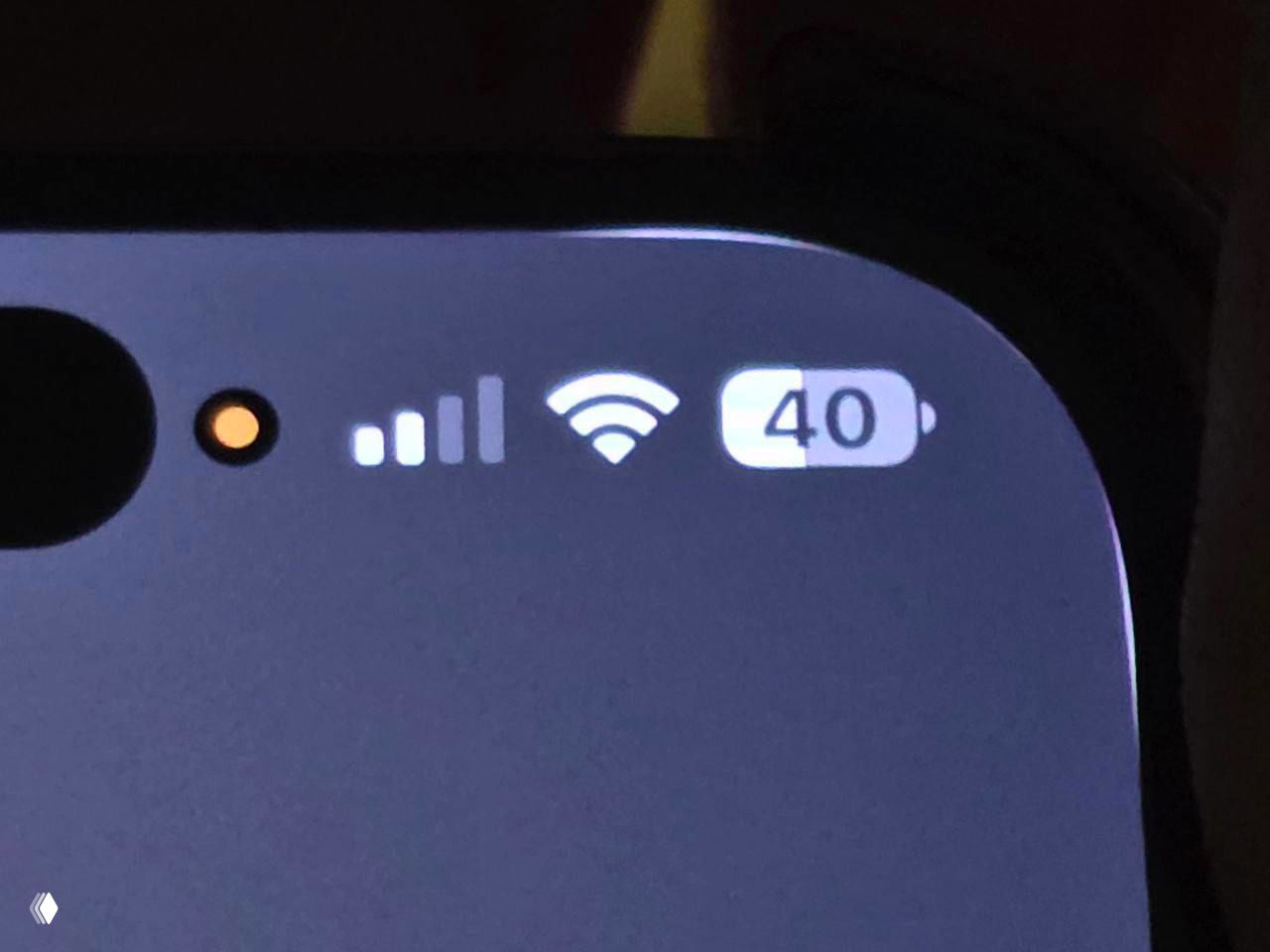 Крупный план индикаторов в правом верхнем углу iPhone: значки сигнала, Wi‑Fi и батареи окружены белой рамкой из‑за закруглений iOS 26.