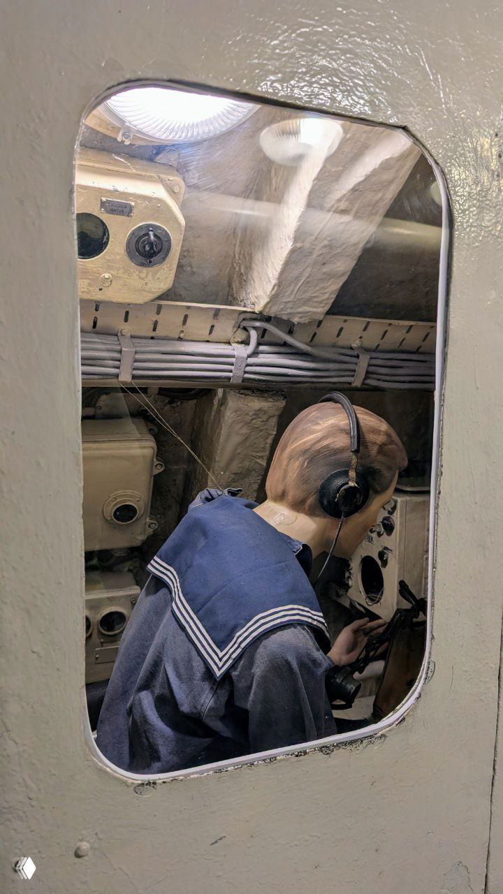 Манекен моряка в форме за пультом управления внутри подлодки С-56 — музейная диорама, показывающая рабочее место радиометриста или рулевого.