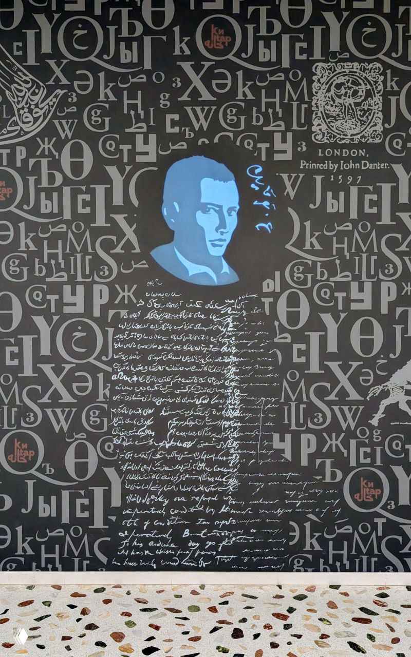 Деталь настенной графики или плаката с изображением портрета и многочисленными символами и буквами, как часть выставки, посвящённой типографике.