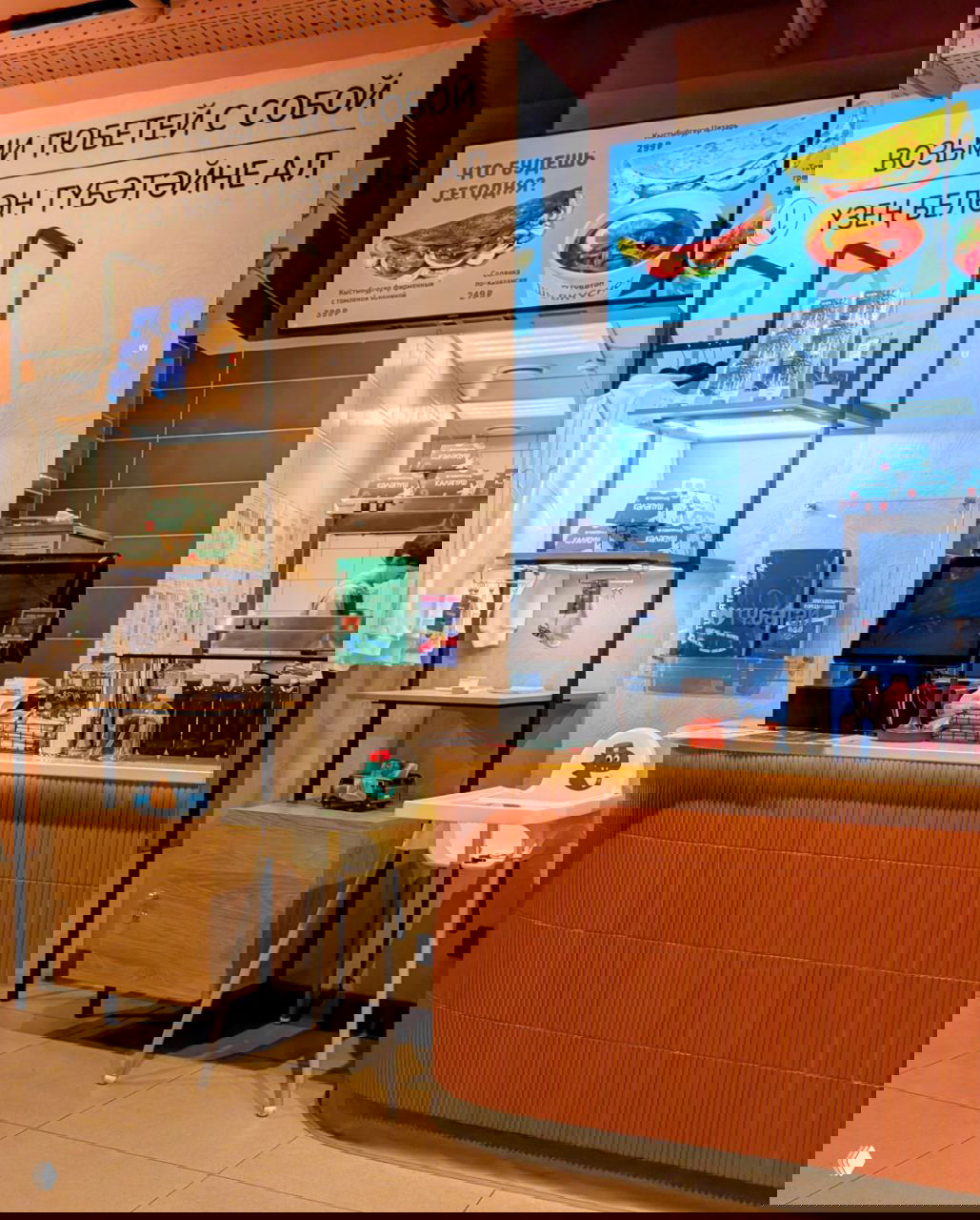 Интерьер точки «Тюбетей»: кассовая зона, меню на экранах, стеллажи с брендированной упаковкой и надпись 'Возьми тюбетей с собой' в фирменном оформлении.