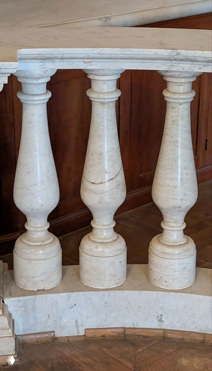 Крупный план мраморных балясин лестничного ограждения в Гатчине; на центральной видно трещину — оригинальная балясина среди восстановленных.