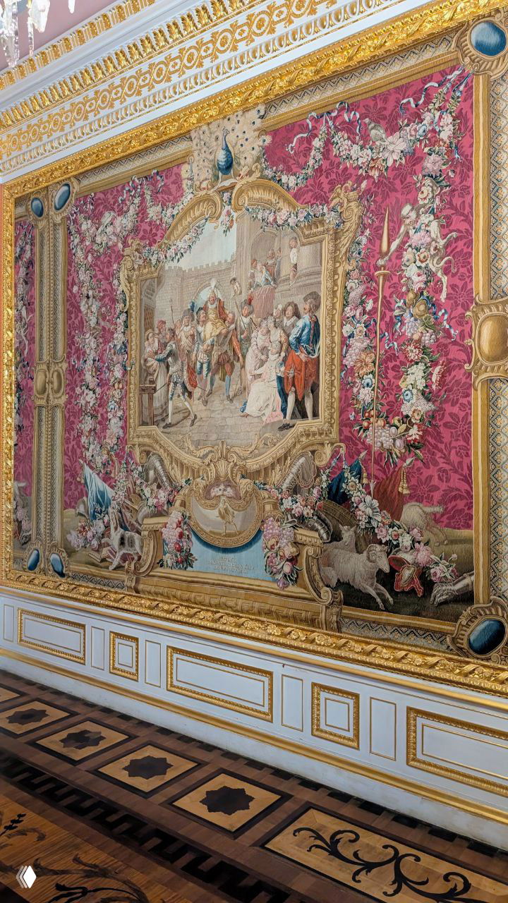 Фрагмент крупного французского гобелена в Малиновой гостиной Гатчинского дворца: насыщенные розовые тона, сюжетная сцена и богатая рамка.