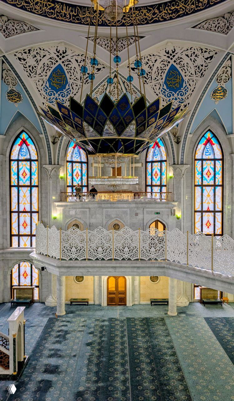 Интерьер мечети Кул Шариф: балконы, резные ограждения и большой центральный лоскутный люстру, окна с витражами и молитвенный ковер.
