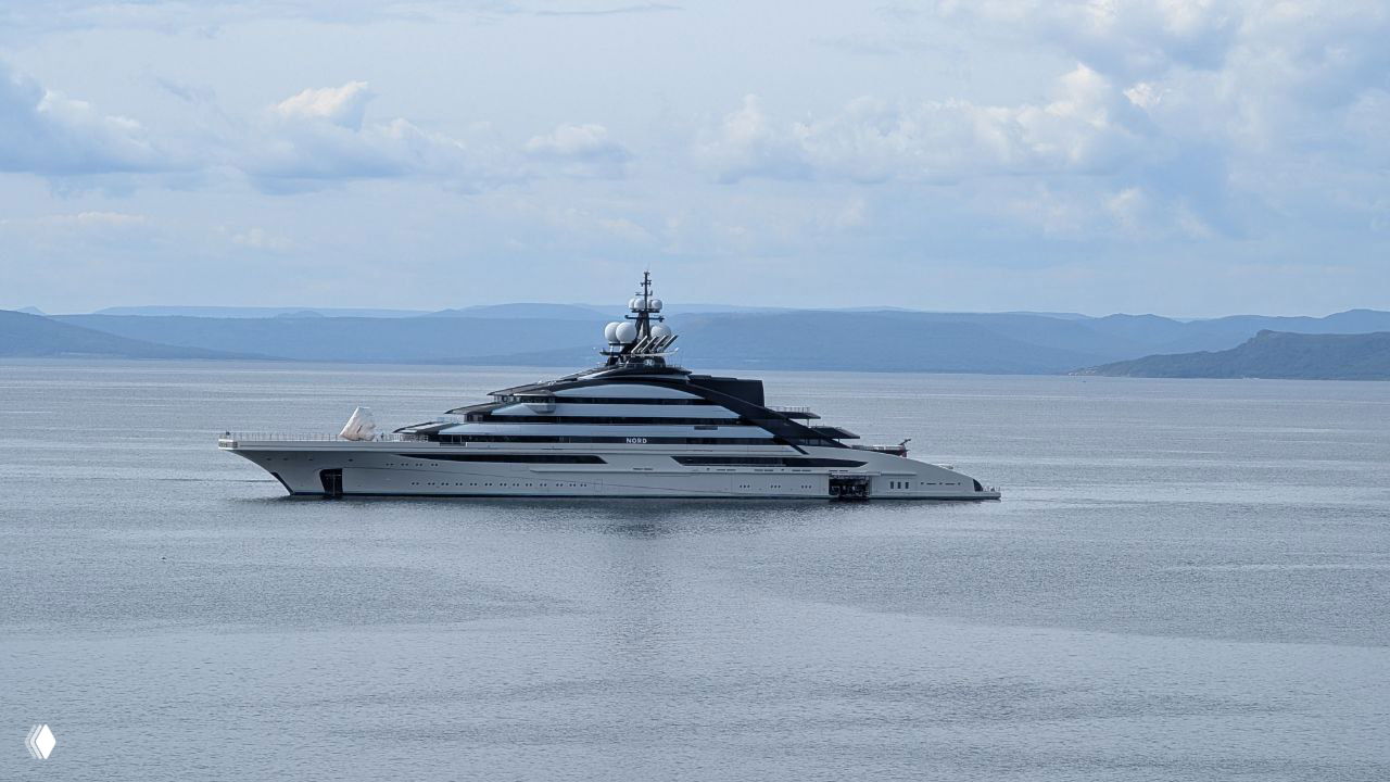 Большая белая яхта на фоне спокойной поверхности бухты и низких дальневосточных сопок — морской пейзаж у побережья Владивостока