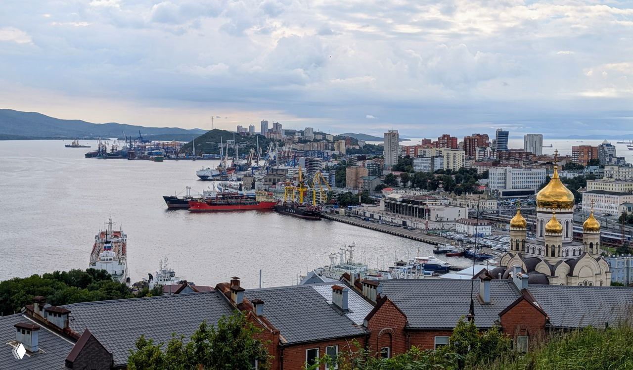 Панорамный вид на город, набережную и купол собора: городской пейзаж Владивостока с высоты, крыши и причалы на переднем плане