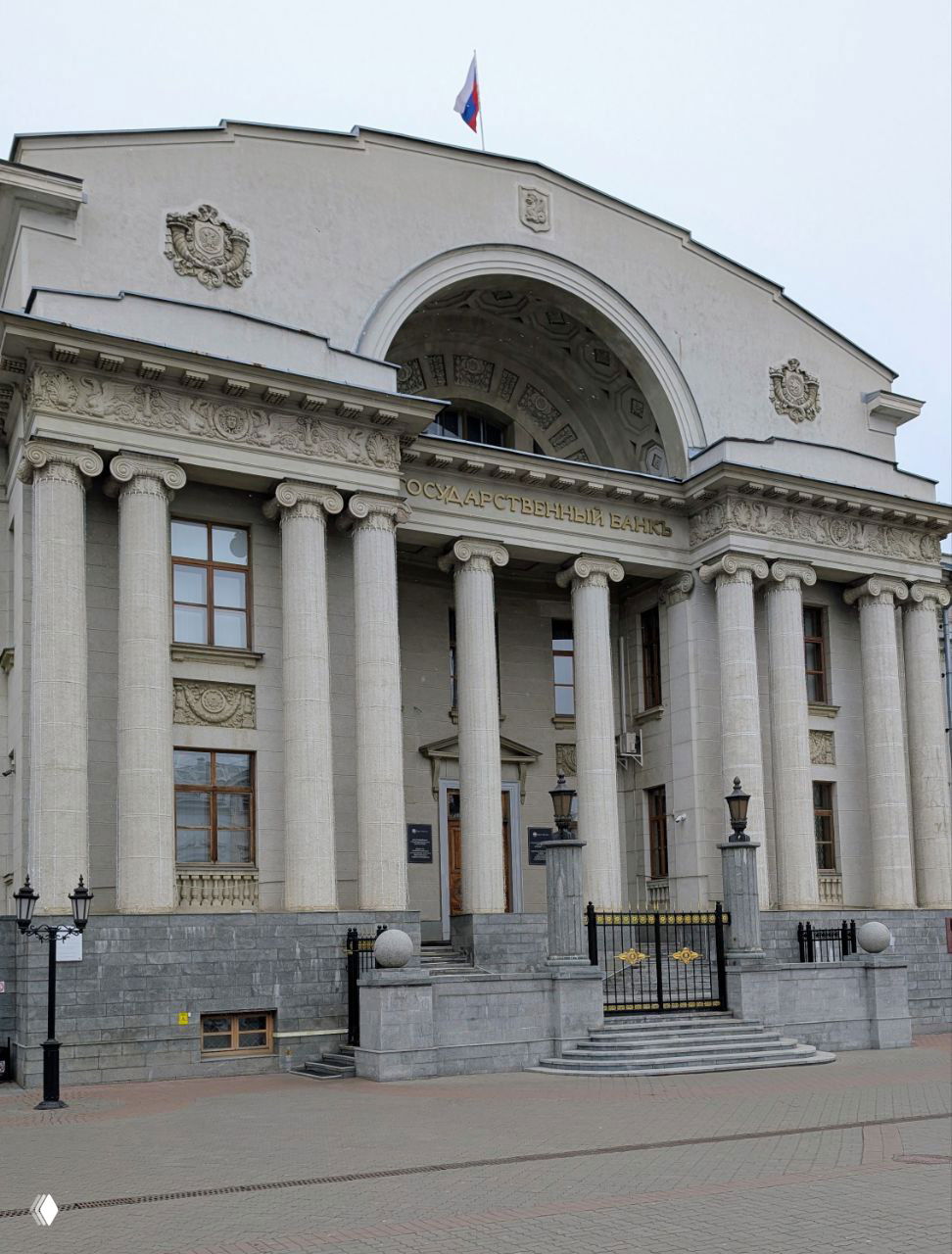 Фасад здания Национального банка в Казани с колоннадой и надписью, вид на главную улицу при ровной зимней освещенности.