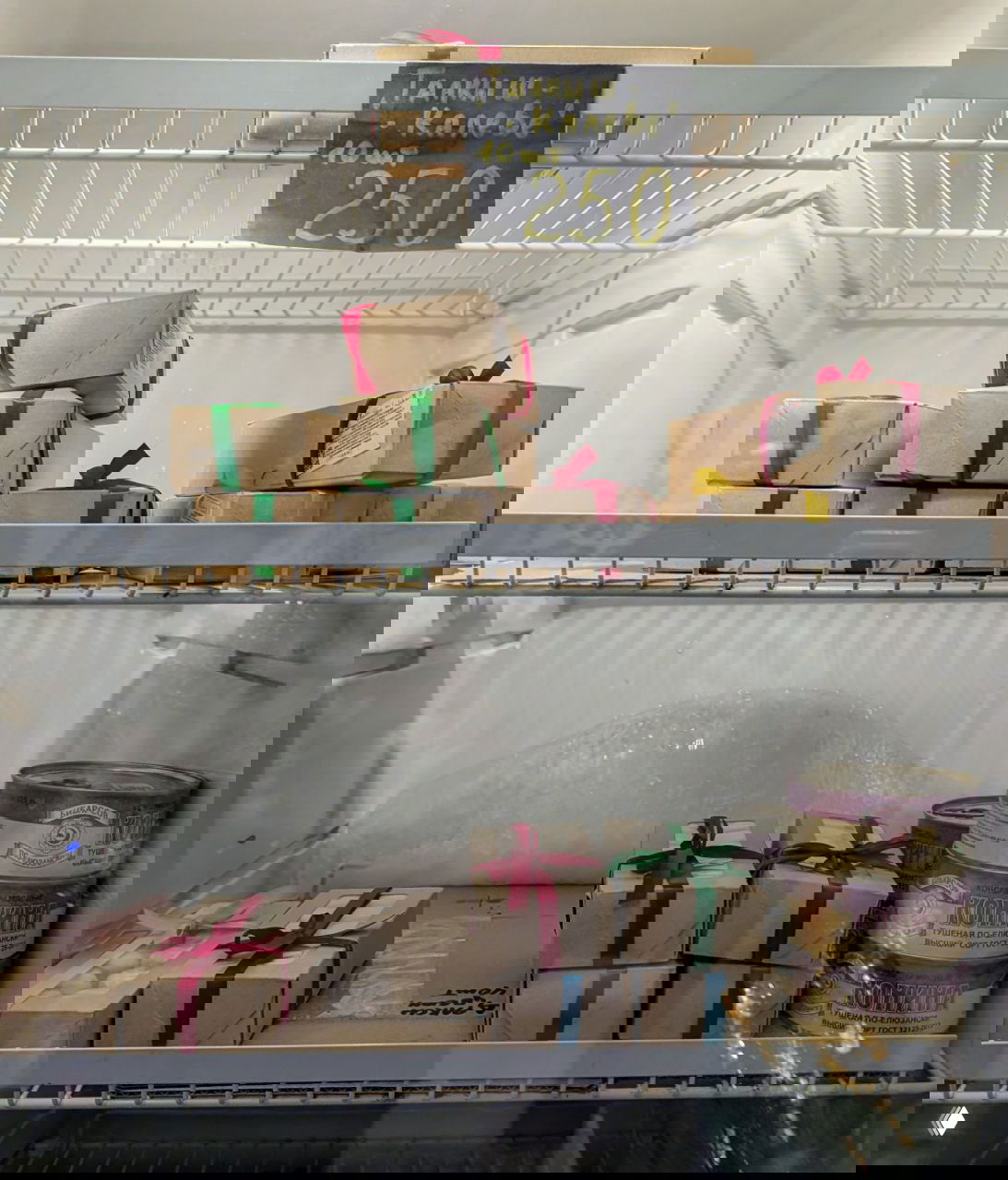 Холодильная витрина с коробками талкыш калеве по 250 ₽ и консервами конины — сладости и продукты на прилавке.