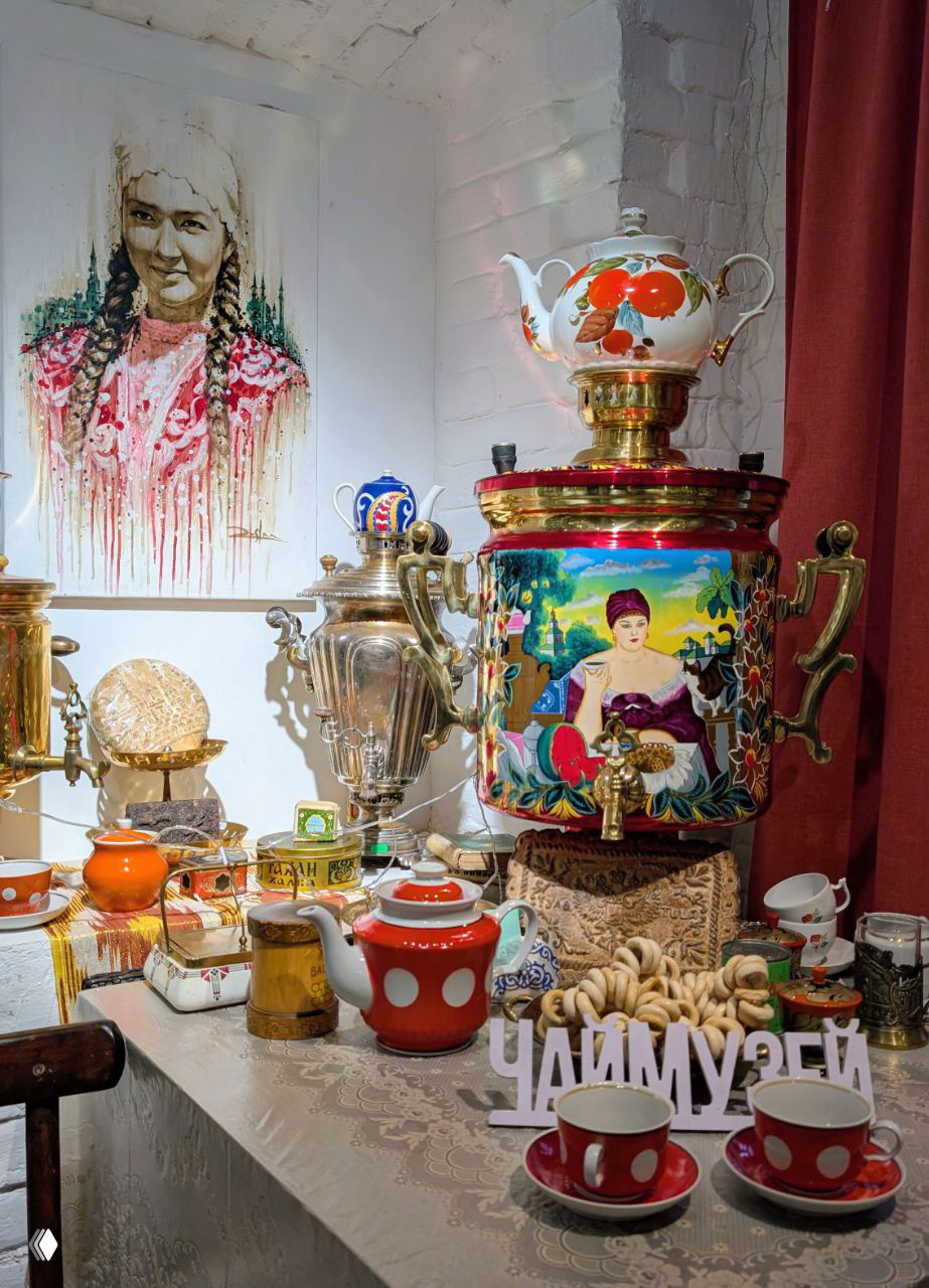 Яркая экспозиция с расписным самоваром, чашками и декоративными предметами, композиция с надписью ЧАЙМУЗЕЙ и расписными чашечками на столе