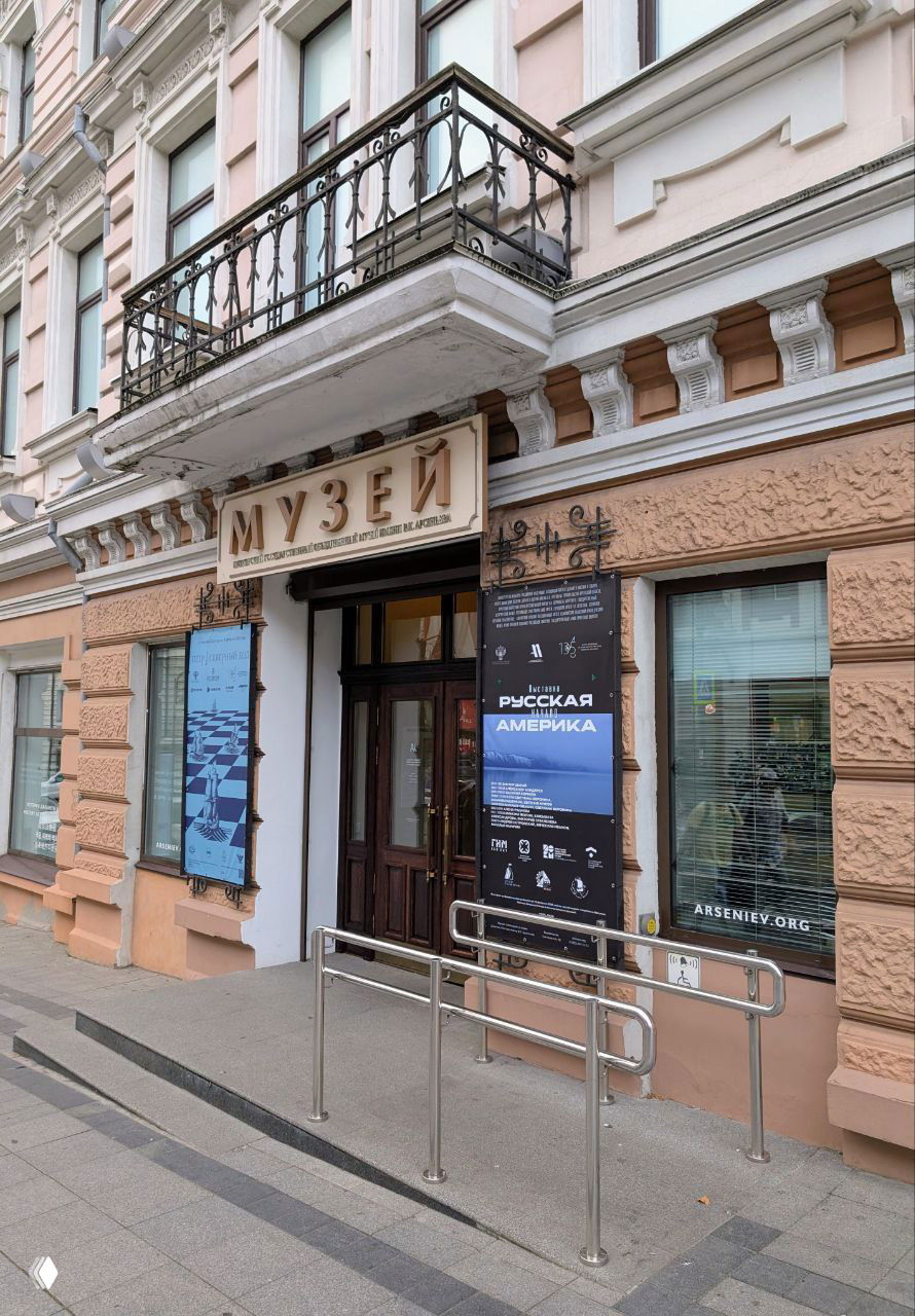 Фасад входа в Музей истории Дальнего Востока имени Арсеньева во Владивостоке с афишами выставок «Русская Америка» и информацией у двери.