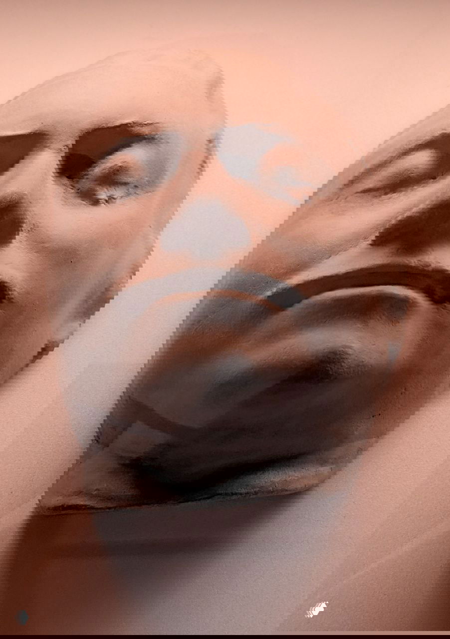 Крупный план белой гипсовой маски или слепка лица из музейной витрины — строгий ракурс с акцентом на черты лица и светотень.