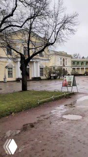 Дворцовый двор и прогулочная зона при пасмурной погоде: дорожки, вывески и архитектура хозяйственных строений рядом с основным корпусом.