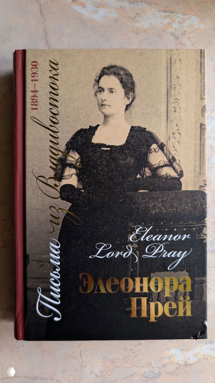 Обложка книги «Элеонора Лорд Прей. Письма из Владивостока» с портретом женщины и русскими и английскими надписями на фоне столешницы.