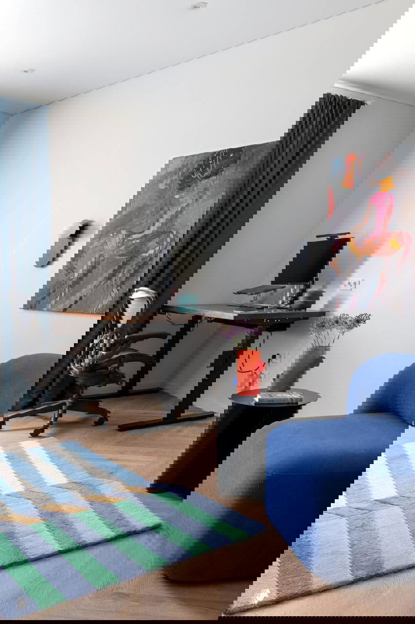 Кабинет/гостевая зона: рабочий стол с эргономичным креслом, синий модульный пуф и полосатый коврик в сине-зеленой гамме.