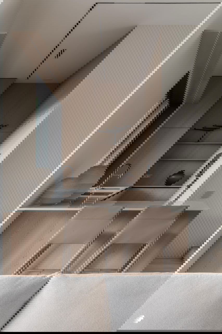 Минималистичная кухня-остров с деревянными фасадами, барными стульями и белой столешницей — натуральные материалы и сдержанная гамма.